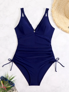 Costume intero blu scuro con scollo a V e laccetti laterali su sfondo in marmo
