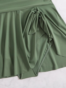 Detail of dark green plus size swim skirt with knot tie on marble background