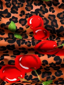 Macro shot of high-stretch swimsuit fabric with brown leopard print and red cherry pattern