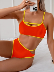 Detail of orange bikini with yellow contrast trim and waist cut-outs shown on a model