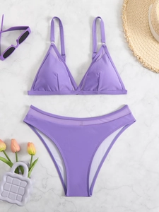 Flat lay of a lavender bikini set with mesh trim and beach accessories on marble