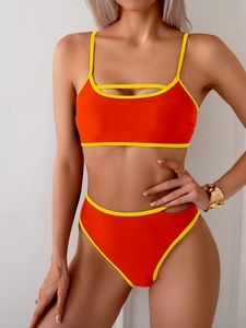 Detailed front view of high-waisted orange bikini with fluorescent yellow trim and cut-outs