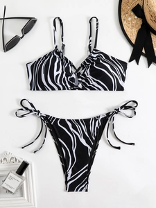 Flat lay of a zebra print two-piece bikini set with side-tie bottoms and beach accessories
