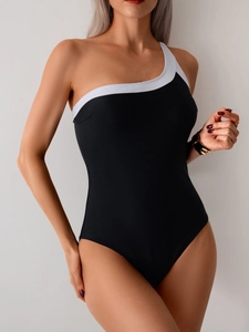 Detail of one-shoulder one-piece swimsuit featuring elegant black and white color block