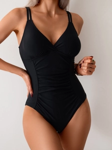 Detail of black one-piece swimsuit featuring deep V-neck and ruched waist fabric texture