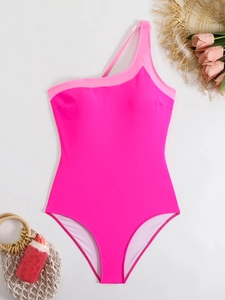 Flat lay of one-shoulder pink one-piece swimsuit with summer vacation accessories