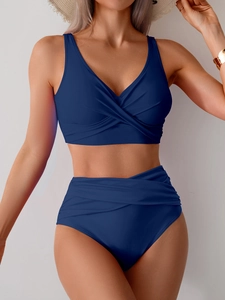 Detail of high-waisted dark blue bikini featuring crossover twisted V-neck and ruched tummy control