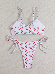 Flat lay of a white two-piece bikini featuring a sweet red cherry print with tie details