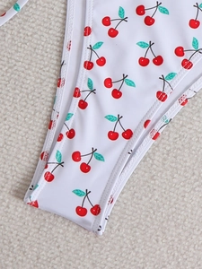 Close-up of white bikini bottoms featuring cherry print with fine stitching details
