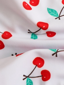 Macro shot of white bikini fabric featuring vibrant red cherry prints and subtle texture