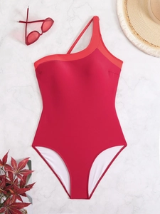 Flat lay of a red one-shoulder swimsuit with sunglasses and a straw hat on marble
