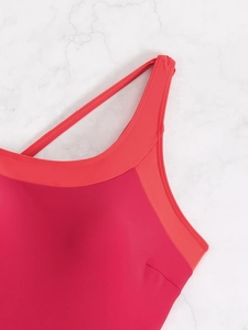 Detail of cross strap design and flat seams on vibrant red athletic swimwear