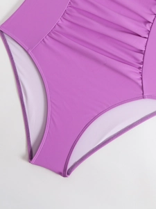 Detailed close-up of purple ruched fabric and high-waist design on a swimsuit