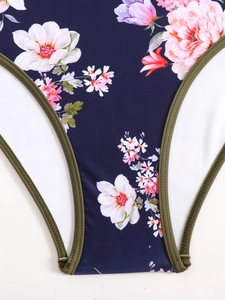 Detail of floral one-piece swimsuit showing navy fabric with pink flowers and green stitching