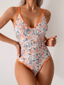 Detailed view of one-piece swimsuit with floral print, deep V-neck and orange straps