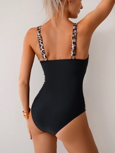 Back view of black one-piece swimsuit with leopard print straps and open back design