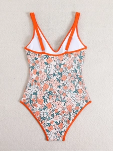 Flat lay of floral one-piece swimsuit with orange straps and vibrant flower pattern