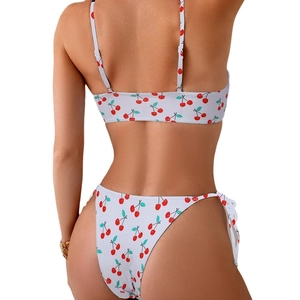 White bikini set with red cherry print featuring spaghetti straps and side tie bottoms