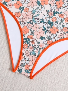 Close-up of floral one-piece swimsuit with orange trim and high-quality stitching detail