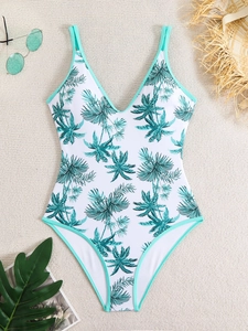 Flat lay of a white one-piece swimsuit with green palm leaf print and thin mint straps