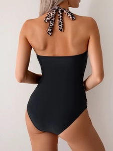 Detail of a black one-piece swimsuit with leopard print halter straps and side panels