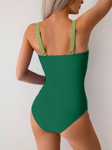 Detail of deep green one-piece swimsuit featuring adjustable lime green shoulder straps