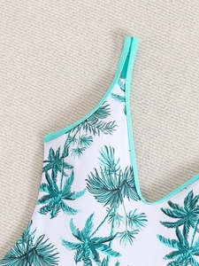 Detail of the V-neckline and straps on a white swimsuit with green palm tree patterns