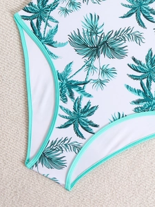 Detail of white swimsuit with tropical palm leaf print and mint green elastic trim