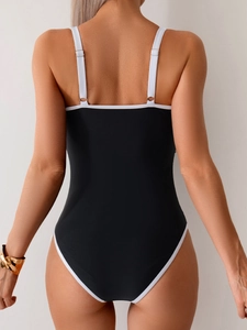 Detail view of the back of a black one-piece swimsuit with white adjustable straps