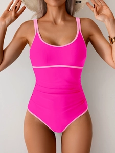 Detail of rose red one-piece swimsuit featuring contrast piping and slimming waist pleats