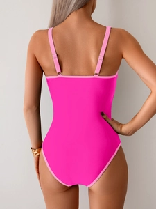 Detail view of hot pink one-piece swimsuit featuring a deep backless design and thin straps