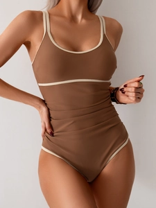 Detail of coffee brown one-piece swimsuit featuring contrast piping and ruched tummy control