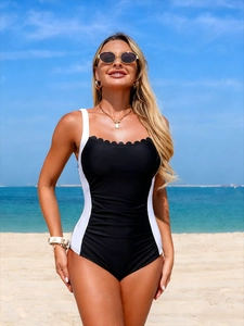 Close-up of black and white one-piece swimsuit with scalloped neckline and ruched waist