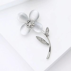 Détail macro d'une broche fleur en opale avec incrustation de zircon sur fond blanc