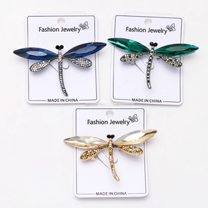 Detail of dragonfly brooches featuring crystal wings in blue, green, and champagne gold