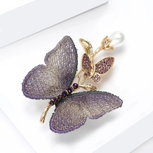 Makro-Detail einer eleganten Stoff-Brosche mit lila Netzhautflügeln und Glitzersteinen