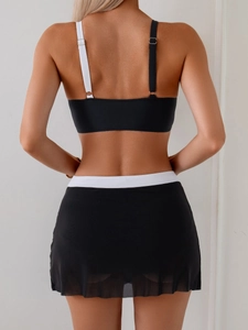 Rear view of black two-piece bikini featuring mesh skirt and white contrast waist band