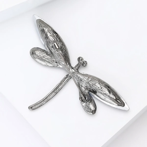 Detailed back view of silver dragonfly brooch showing the safety pin clasp and texture