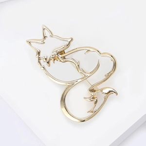 Close-up of golden hollowed-out fox brooch with smooth metallic lines on white background