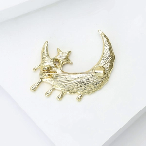 Détail du dos d'une broche lune et étoile dorée montrant l'épingle et la texture brossée