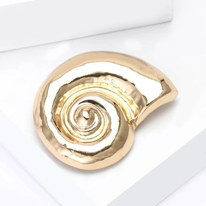 Detail of a matte gold snail shell brooch showing high-polished spiral texture and alloy finish