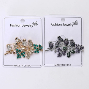 Detail of five-bird brooch on branch with crystal embellishments in gold and silver