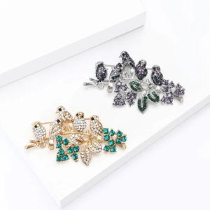 Elegant gold and silver brooches with crystal-encrusted birds resting on a branch