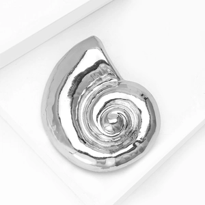 Macro detail of silver nautilus snail shell brooch with polished metallic texture