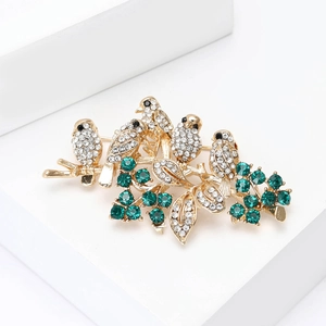 Detailed view of Five Birds on Branch Brooch with sparkling rhinestones and green berries