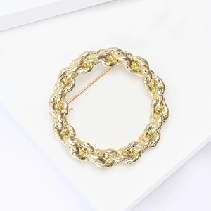 Macro view showing the golden twisted rope texture and clasp of the round vintage brooch