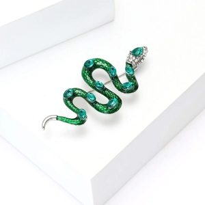 Détail macro de la broche serpent en émail avec pierres précieuses vertes et cristaux sur argent