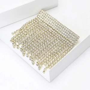 Close-up of sparkling rhinestone tassel brooch with gold metal fringe on white stand