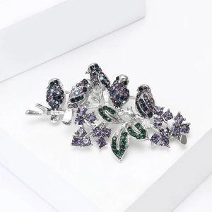 Detailed close-up of bird brooch with sparkling crystals on minimalist white pedestal