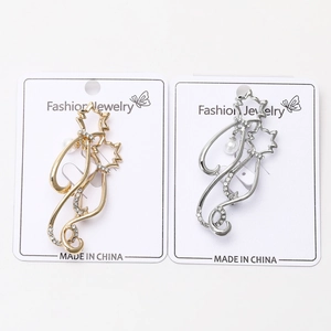 Vue détaillée de broches chat élégantes en or et argent avec cristaux et perles sur carte